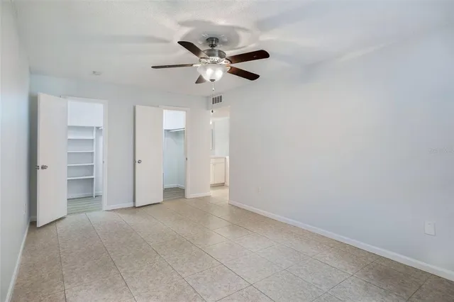 an empty room with closet and a ceiling fan