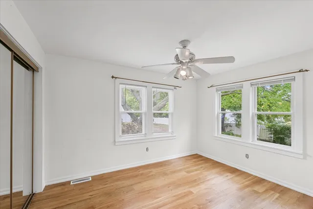 a view of empty room with wooden floor and fan
