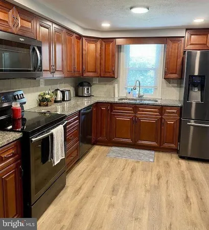 a kitchen with stainless steel appliances granite countertop a stove a sink dishwasher and a microwave oven with cabinets