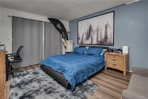 a bedroom with a bed wooden floor and painting on the wall