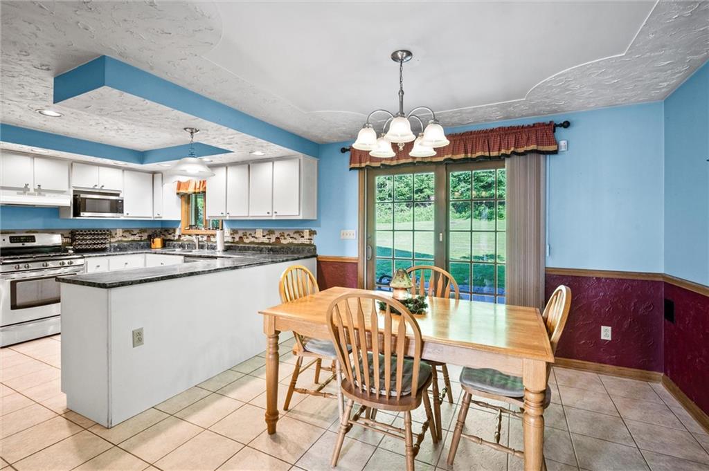 206 Harbison Road Sarver, PA 16055 - Photo 5 of 46 a kitchen with stainless steel appliances granite countertop a stove top oven a dining table and chairs with wooden floor