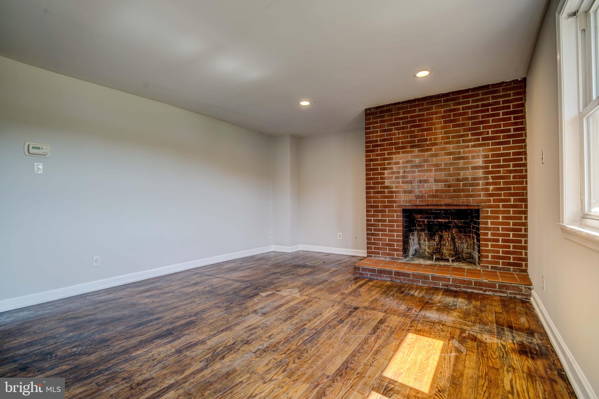 1930 Solomons Island Road Huntingtown, MD 20639 - Photo 3 of 21 an empty room with wooden floor and fireplace