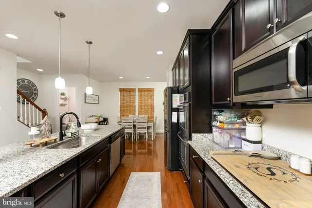 a kitchen with stainless steel appliances granite countertop a sink a stove and a wooden floors