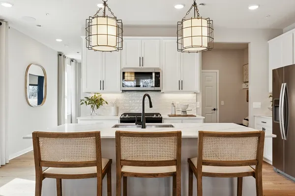 a kitchen with stainless steel appliances granite countertop a dining table chairs a microwave oven and a refrigerator with wooden floor