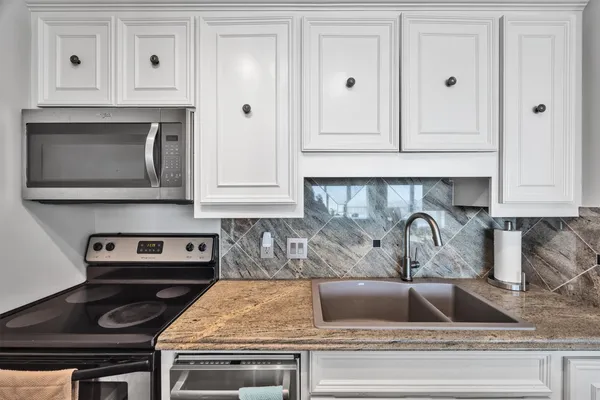 a kitchen with white cabinets and a stove top oven