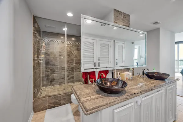 a bathroom with a granite countertop sink and a shower