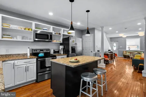 a kitchen with stainless steel appliances granite countertop a sink a stove and a wooden floors