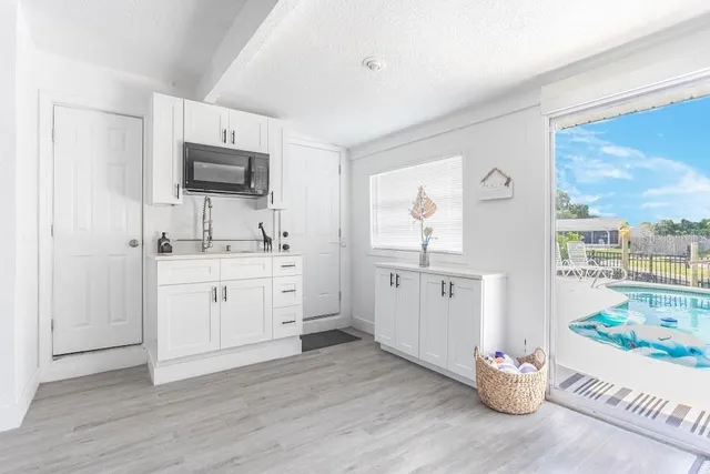 a kitchen with kitchen island white cabinets a sink a window and stainless steel appliances