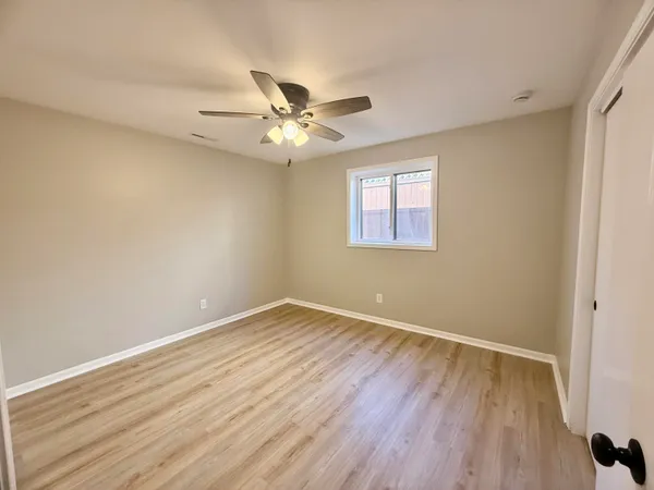a view of empty room with wooden floor and fan