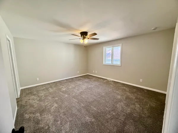 an empty room with windows and chandelier fan