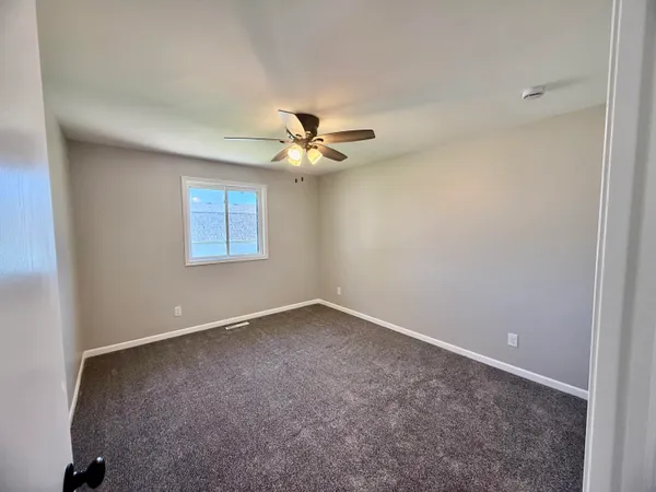 an empty room with a window and a ceiling fan