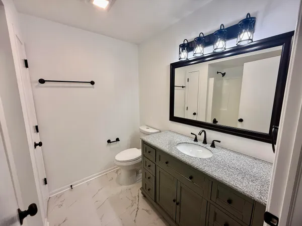 a bathroom with a granite countertop sink toilet and mirror