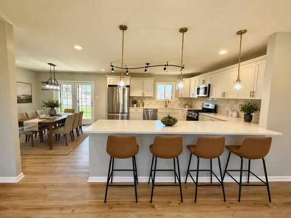 a kitchen with stainless steel appliances kitchen island granite countertop a table chairs and a wooden floor