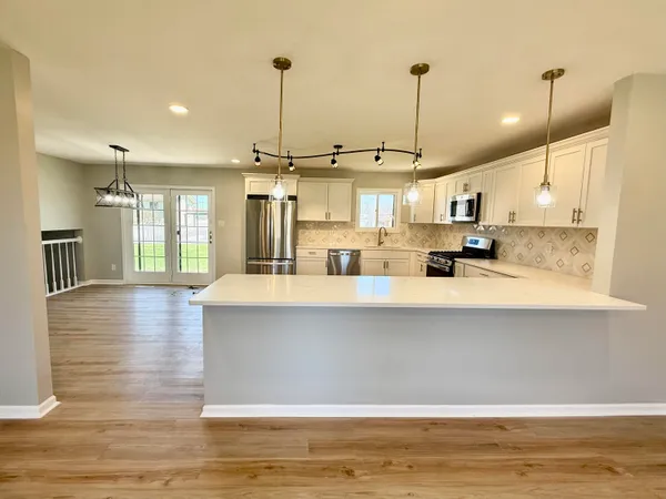 a large kitchen with stainless steel appliances kitchen island granite countertop a table chairs and a wooden floor