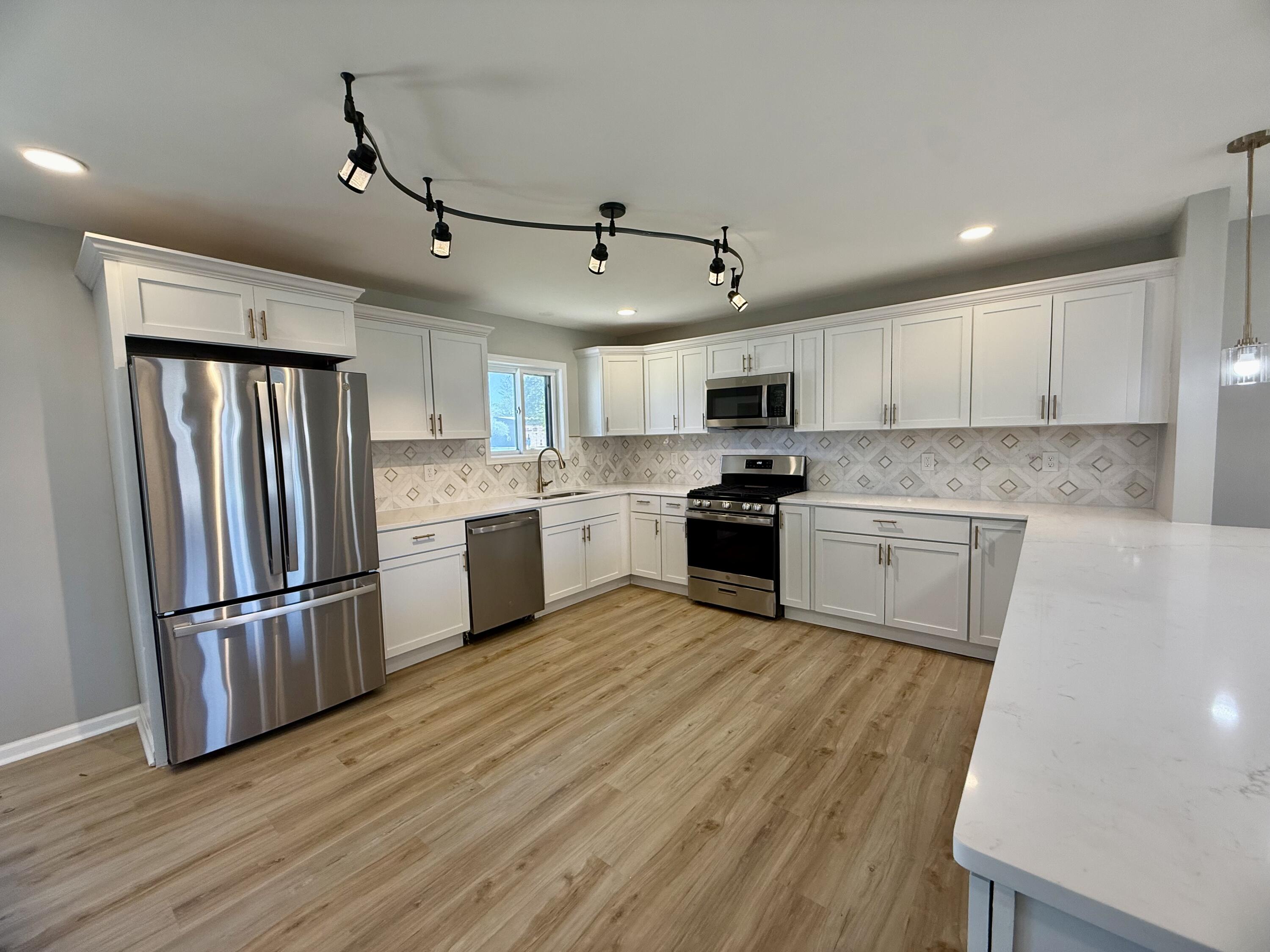 601 Holly Lane Griffith, IN 46319 - Photo 9 of 44 a kitchen with wooden floors white cabinets and stainless steel appliances