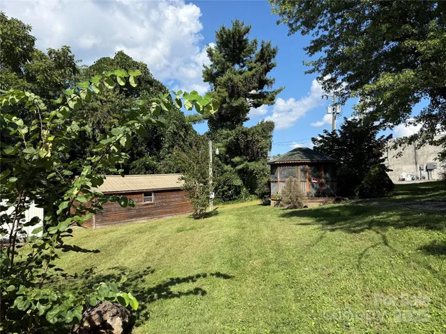 a backyard of a house with table and chairs and a large tree