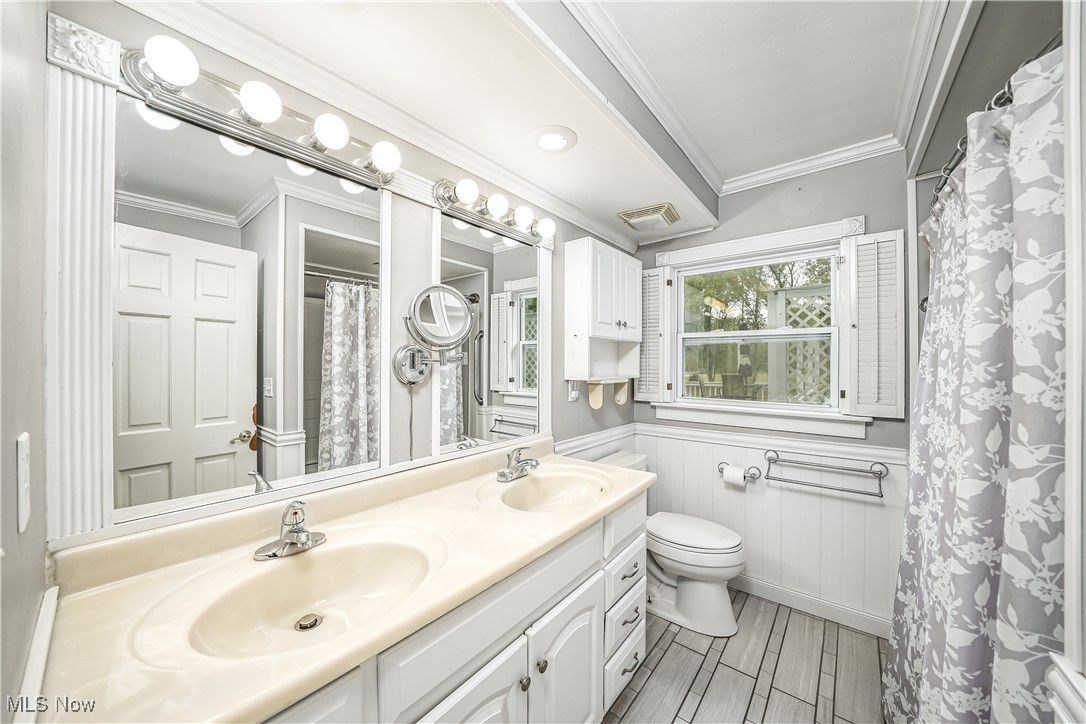 2822 Selkirk Bush Road Warren, OH 44481 - Photo 18 of 50 Bathroom featuring crown molding, double vanity, a wainscoted wall, wood tiled floors, and curtained shower