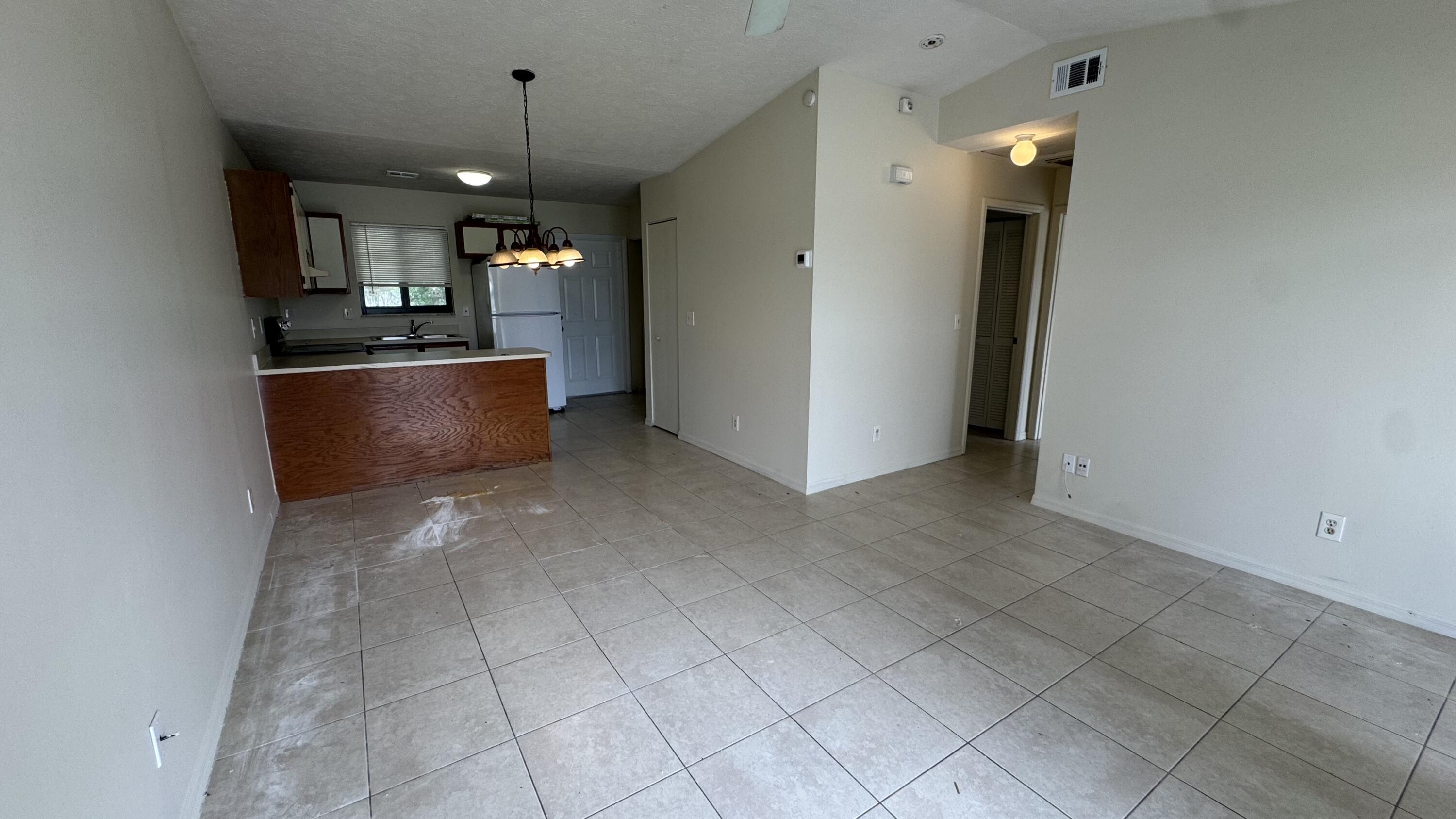 5045 Southeast Primrose Way Stuart, FL 34997 - Photo 2 of 6 an empty room with kitchen and chandelier fan