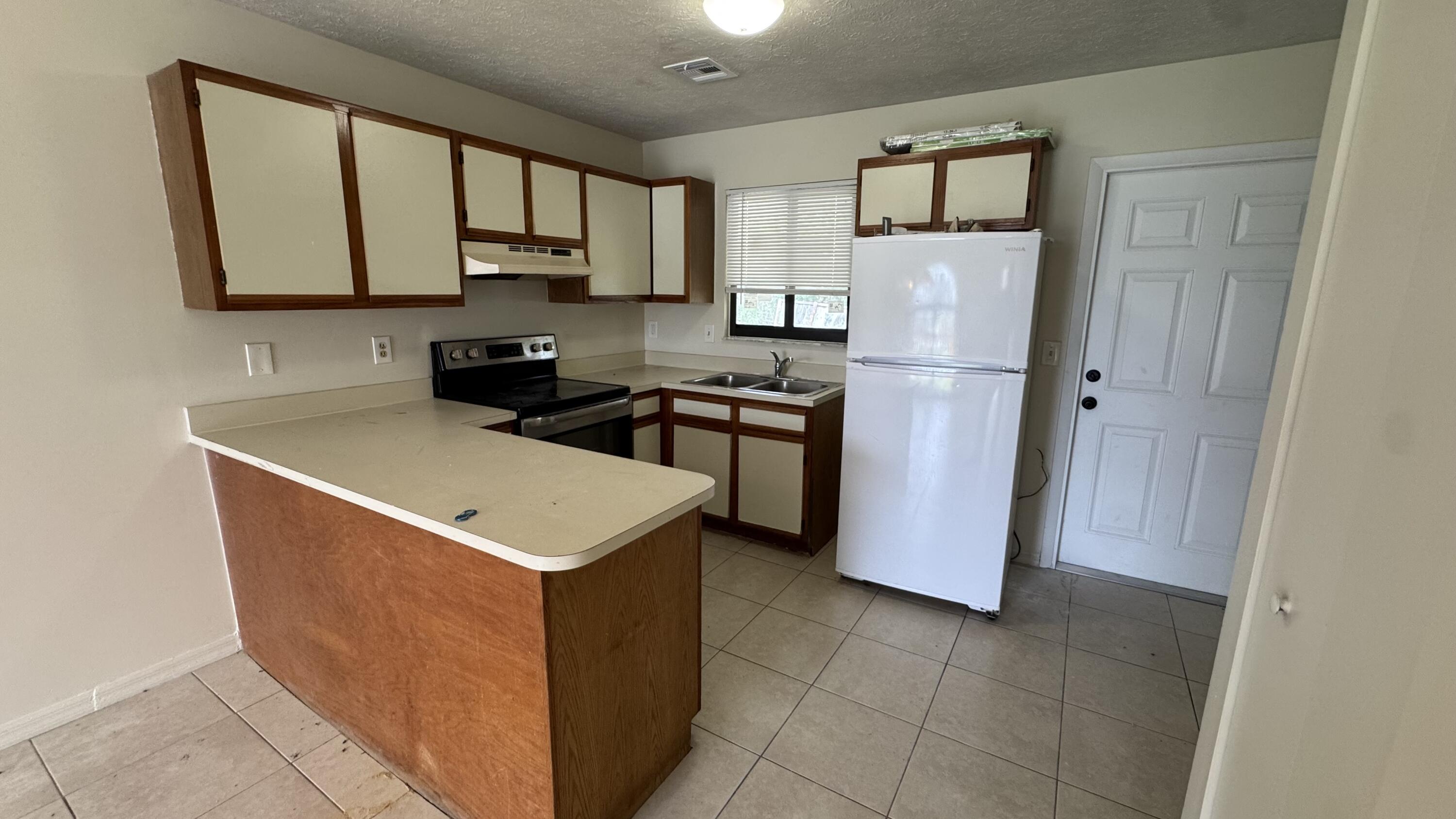 5045 Southeast Primrose Way Stuart, FL 34997 - Photo 3 of 6 a kitchen with stainless steel appliances granite countertop a stove a refrigerator a sink a microwave and cabinets