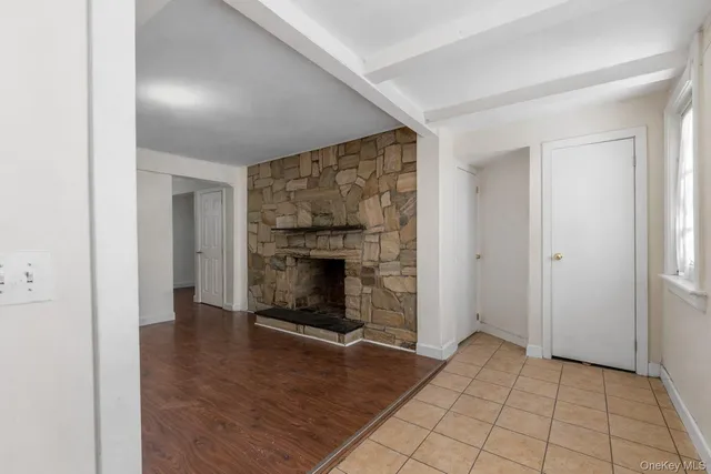 an empty room with wooden floor fireplace and windows