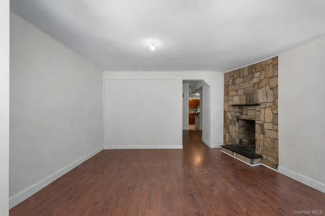a view of an empty room with wooden floor fireplace and a window