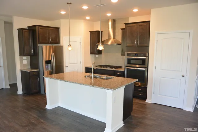 a kitchen with stainless steel appliances granite countertop a refrigerator and a stove top oven