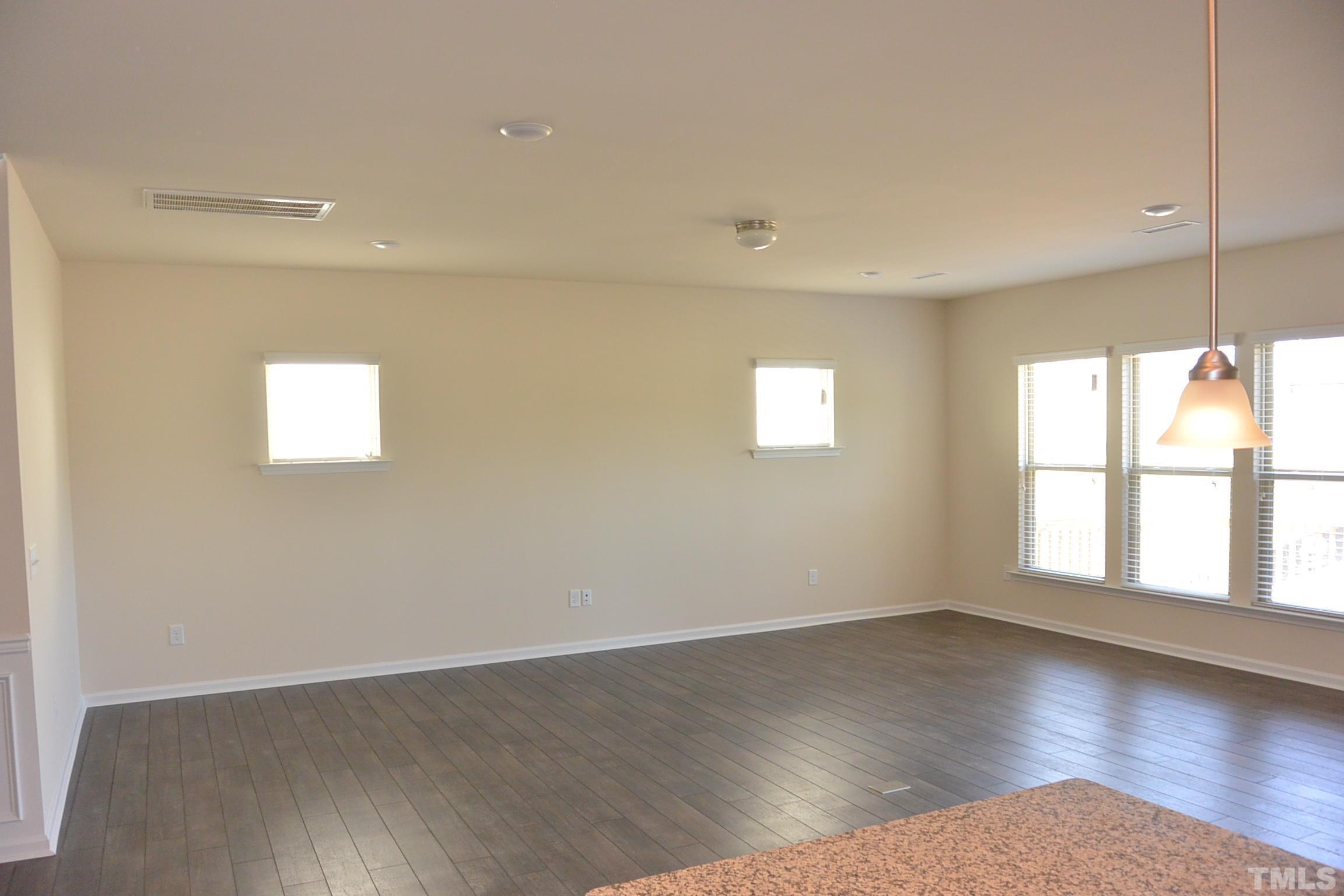 249 Tilth Street Cary, NC 27519 - Photo 7 of 18 an empty room with wooden floor and windows
