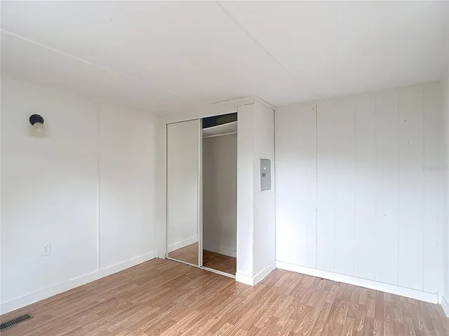 a view of an empty room with wooden floor and closet
