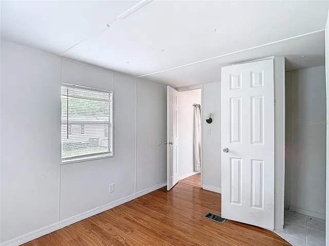 a view of an empty room with wooden floor and a window