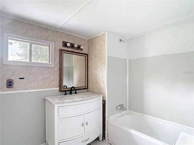 a bathroom with a granite countertop sink a mirror and a bathtub