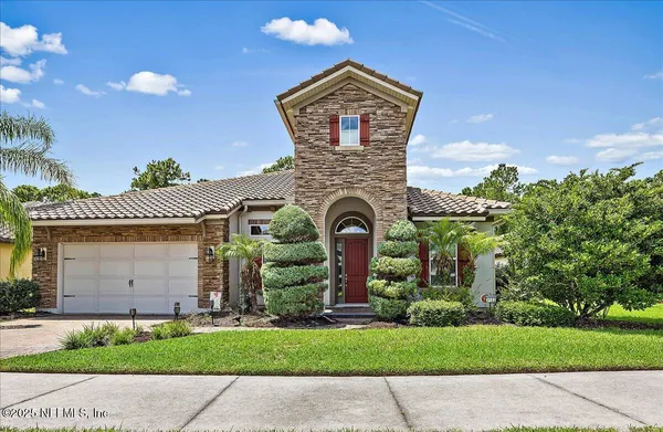 a front view of a house with a garden and trees