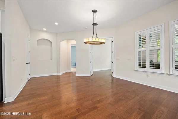 a view of an empty room with window and wooden floor
