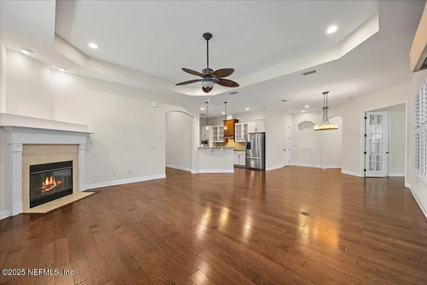a view of a livingroom with a fireplace wooden floor and a ceiling fan