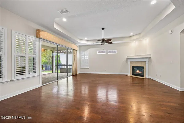a view of an empty room with wooden floor fireplace and a window