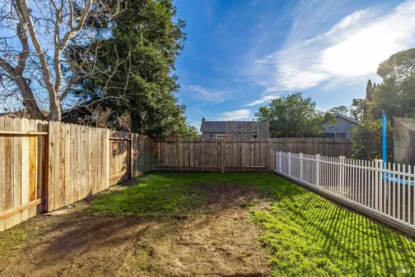 a view of a backyard with wooden fence and trees