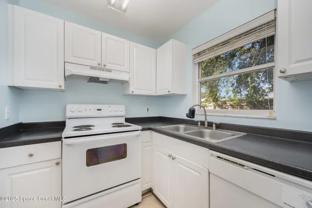 a kitchen with granite countertop white cabinets and white appliances