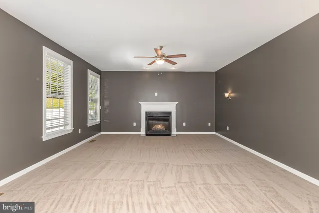an empty room with windows and fireplace