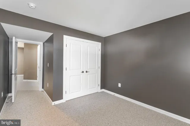 a view of an empty room with closet and a bathroom