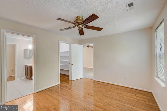 a view of empty room with wooden floor and ceiling fan