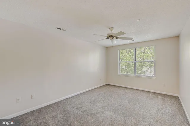 an empty room with a window and a fan