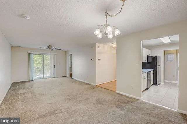 a view of a livingroom with a chandelier fan and windows