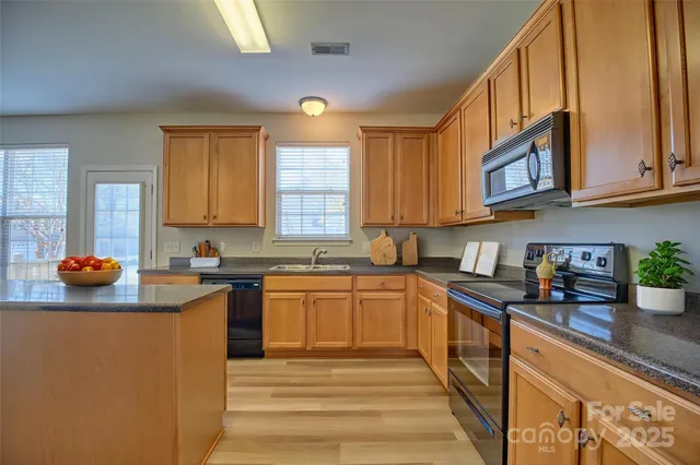 a view of an empty room with a window and a kitchen