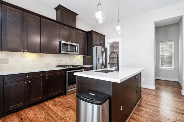 a kitchen with kitchen island a sink appliances a counter space and a window