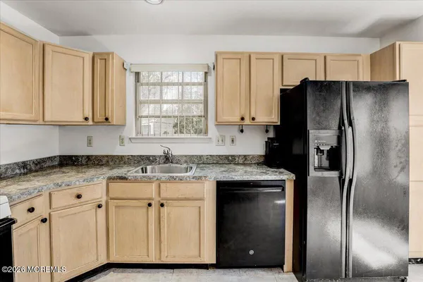 a kitchen with granite countertop a refrigerator sink and cabinets