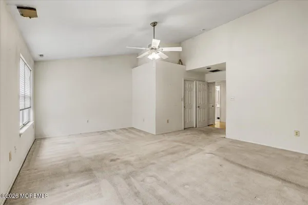 an empty room with a chandelier fan and windows