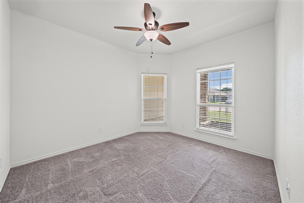 229 Firefly Drive Springtown, TX 76082 - Photo 10 of 33 Vaulted ceiling bedroom with a ceiling fan, two windows, and gray carpeting