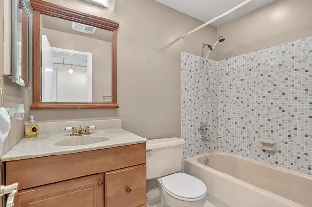a bathroom with a bathtub shower sink mirror vanity and toilet