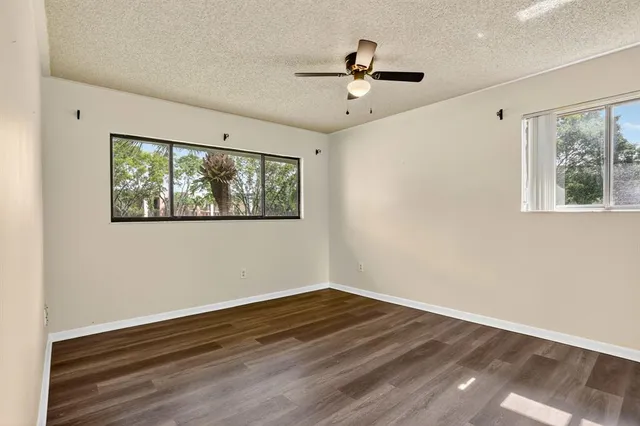 a view of empty room with wooden floor and fan