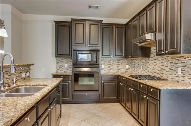 a kitchen with granite countertop a sink stove and cabinets