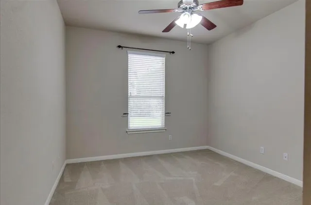 an empty room with a window and a fan